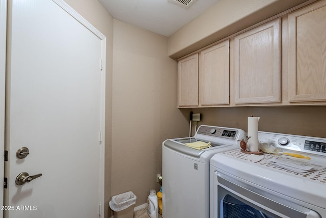 clothes washing area featuring cabinets and separate washer and dryer