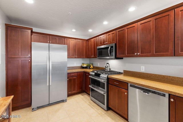 kitchen with appliances with stainless steel finishes, recessed lighting, light countertops, and a textured ceiling