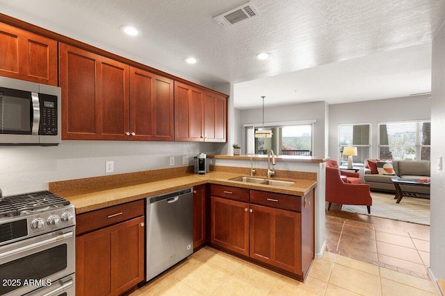 kitchen featuring visible vents, appliances with stainless steel finishes, a peninsula, light countertops, and a sink