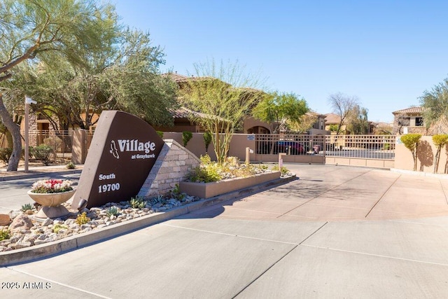 community / neighborhood sign featuring a gate and fence