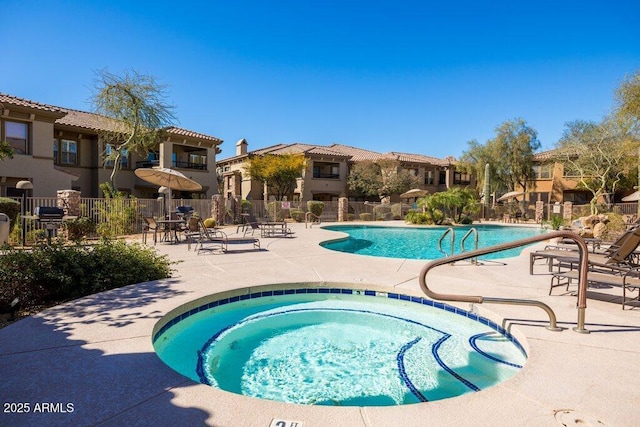 pool featuring a community hot tub, a patio area, fence, and a residential view