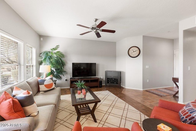 living room featuring ceiling fan, baseboards, and light wood-style flooring