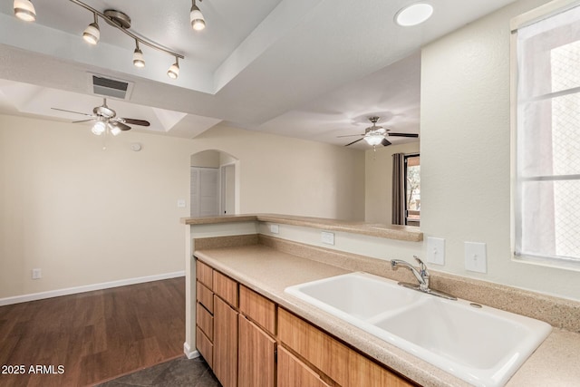 kitchen with a ceiling fan, visible vents, arched walkways, a sink, and light countertops