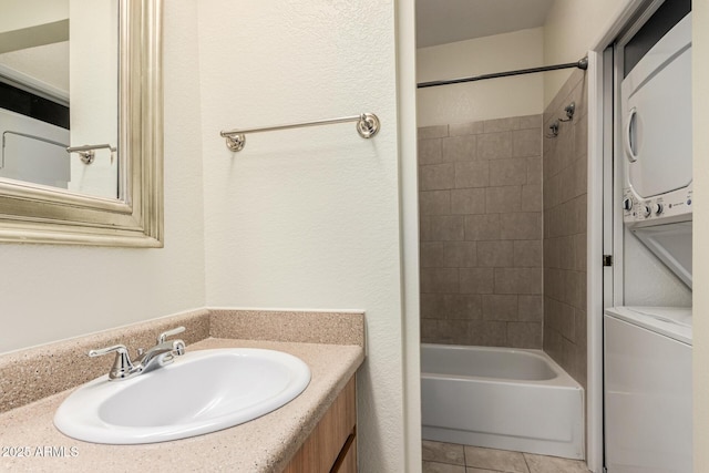 full bath featuring tile patterned flooring, stacked washer and clothes dryer, vanity, and  shower combination