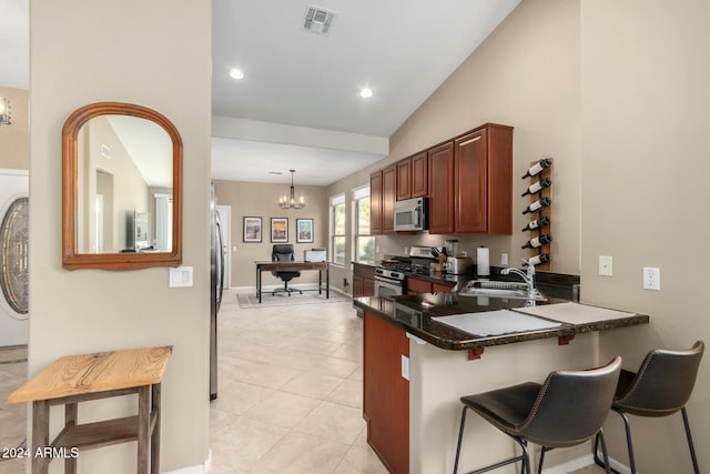 kitchen with kitchen peninsula, appliances with stainless steel finishes, a kitchen bar, sink, and pendant lighting