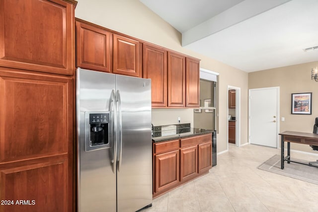 kitchen featuring dark stone countertops, stainless steel fridge with ice dispenser, and light tile patterned floors