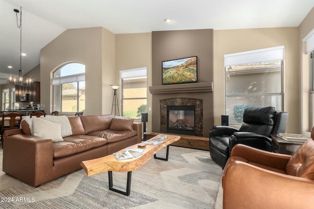 living room featuring a notable chandelier, a premium fireplace, and vaulted ceiling