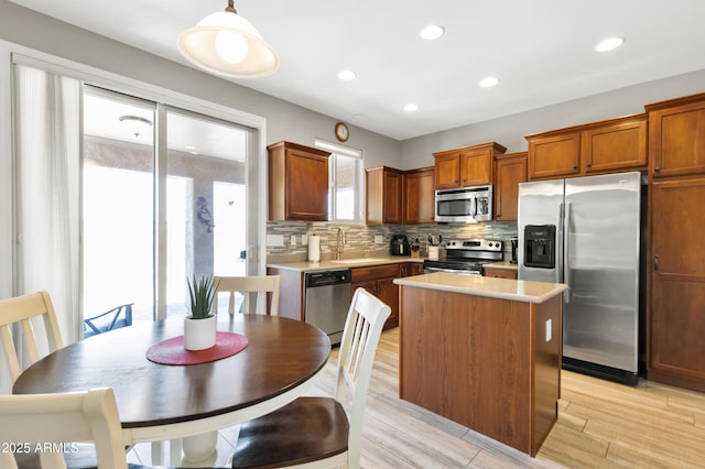 kitchen featuring appliances with stainless steel finishes, a center island, decorative backsplash, light countertops, and recessed lighting