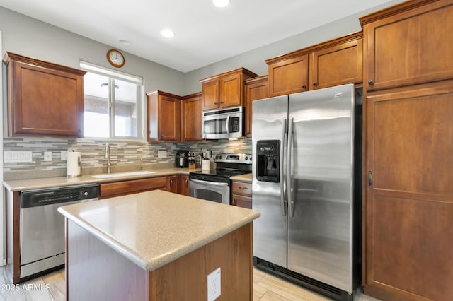 kitchen featuring stainless steel appliances, a sink, backsplash, brown cabinetry, and light countertops