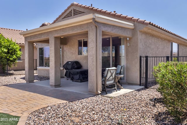 back of house with fence, a patio area, stucco siding, and a tiled roof