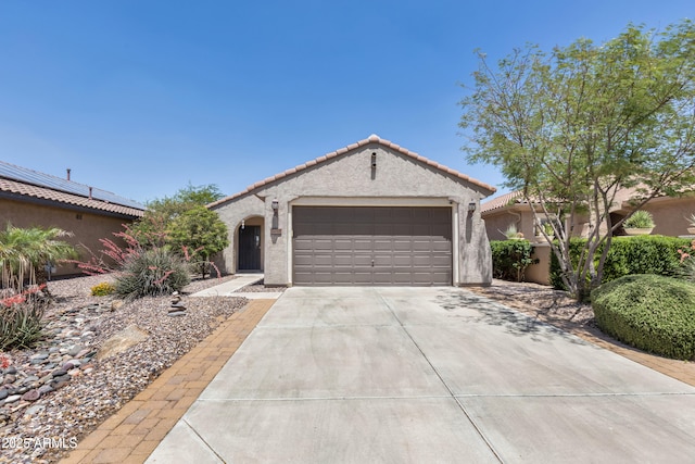view of front facade with driveway, stucco siding, an attached garage, and a tile roof