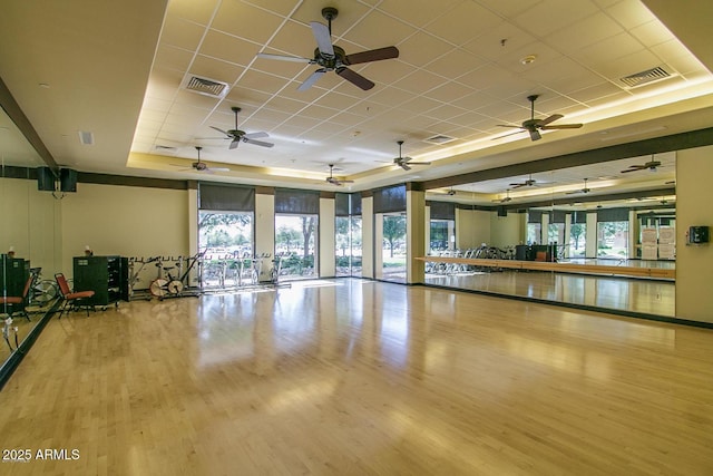 workout area featuring a raised ceiling, wood finished floors, a paneled ceiling, and ceiling fan