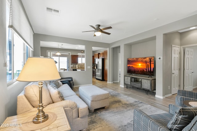 living room with a ceiling fan, light wood-type flooring, and baseboards