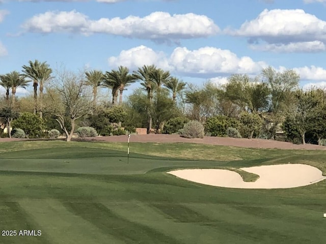 view of home's community with view of golf course, an area to practice putting, and view of wooded area