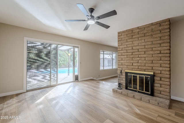 unfurnished living room with light wood-type flooring, a brick fireplace, and ceiling fan