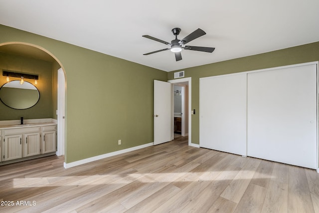 unfurnished bedroom with ceiling fan, sink, light hardwood / wood-style flooring, connected bathroom, and a closet