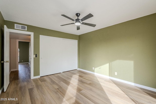 unfurnished bedroom with ceiling fan, light wood-type flooring, and a closet