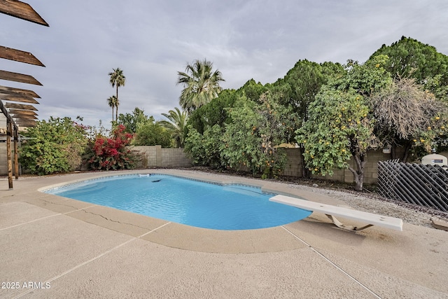 view of pool with a diving board and a patio