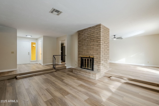 unfurnished living room with ceiling fan, a fireplace, and light hardwood / wood-style flooring