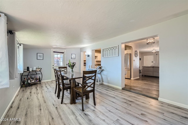 dining area with light hardwood / wood-style floors and a textured ceiling