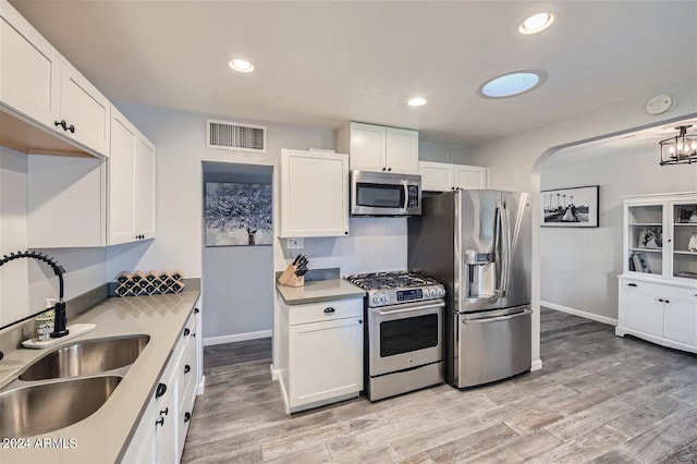 kitchen featuring white cabinetry, sink, appliances with stainless steel finishes, and light hardwood / wood-style flooring