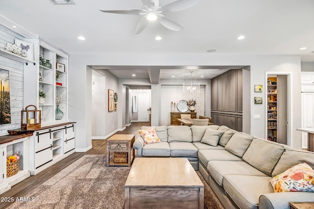 living room with ceiling fan with notable chandelier, dark hardwood / wood-style floors, and built in features