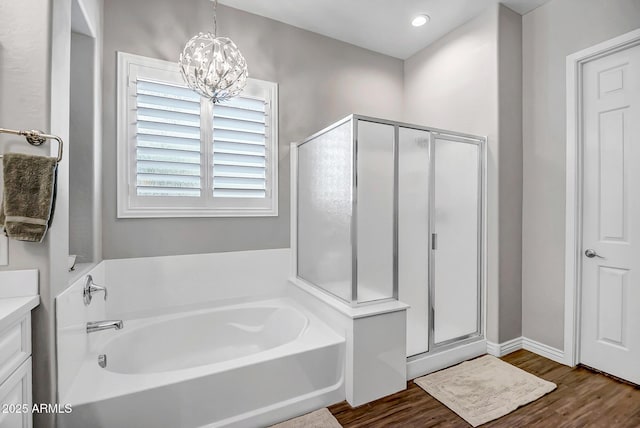 bathroom featuring hardwood / wood-style floors, vanity, separate shower and tub, and an inviting chandelier