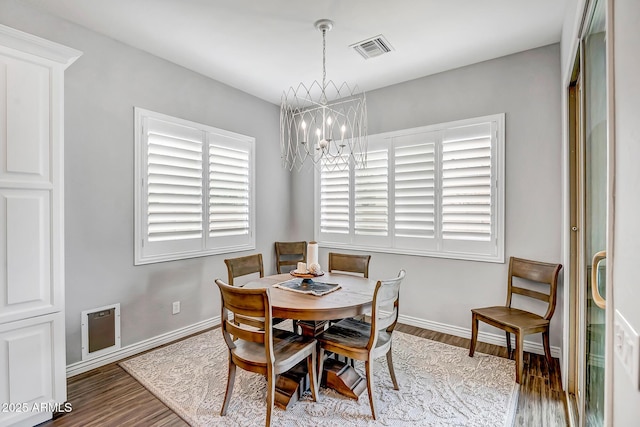 dining space with wood-type flooring and an inviting chandelier