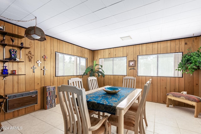 dining room featuring light tile patterned flooring, wooden walls, and heating unit