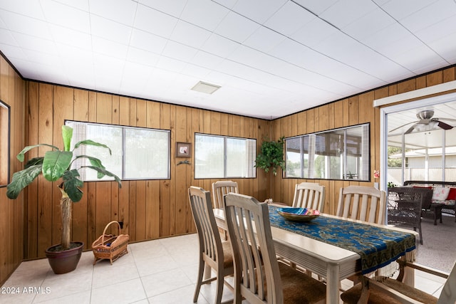 dining room featuring light tile patterned floors, ceiling fan, and wood walls