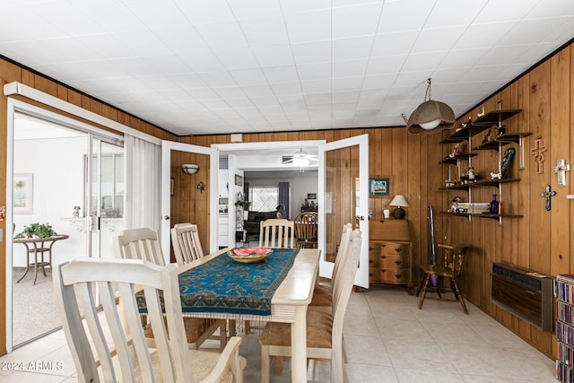 dining room with wood walls, french doors, and light tile patterned flooring