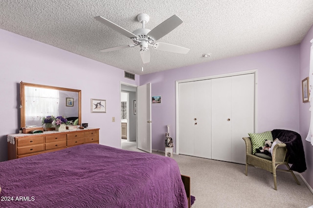 bedroom with a textured ceiling, a closet, ceiling fan, and light colored carpet