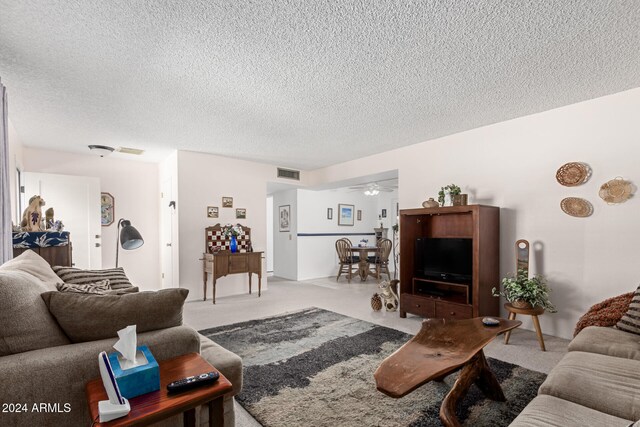 living room with ceiling fan, carpet floors, and a textured ceiling