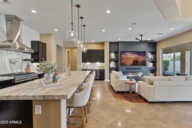 6918 E Ivyglen St, Mesa, AZ 85207 - kitchen with wall chimney range hood, ceiling fan, open floor plan, a center island with sink, and recessed lighting