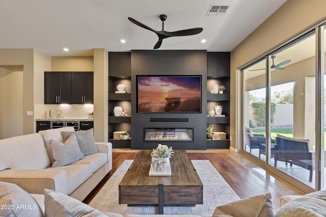 6918 E Ivyglen St, Mesa, AZ 85207 - living room featuring ceiling fan, wood finished floors, a glass covered fireplace, recessed lighting, and built in shelves