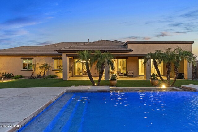 6918 E Ivyglen St, Mesa, AZ 85207 - pool at dusk featuring an outdoor pool, a yard, a patio area, and an outdoor hangout area