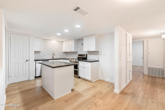 kitchen featuring stainless steel appliances, sink, white cabinets, a center island, and light hardwood / wood-style floors