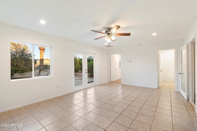 tiled spare room featuring ceiling fan and french doors