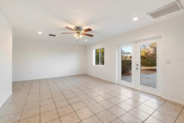 empty room featuring ceiling fan, light tile patterned floors, and french doors