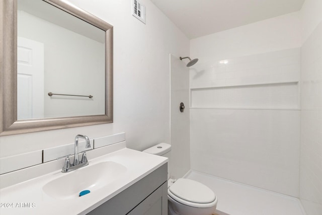 bathroom featuring a tile shower, vanity, and toilet