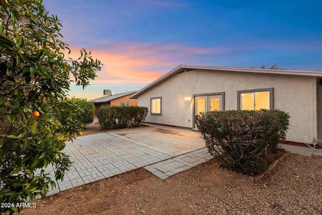 back house at dusk with a patio area and french doors