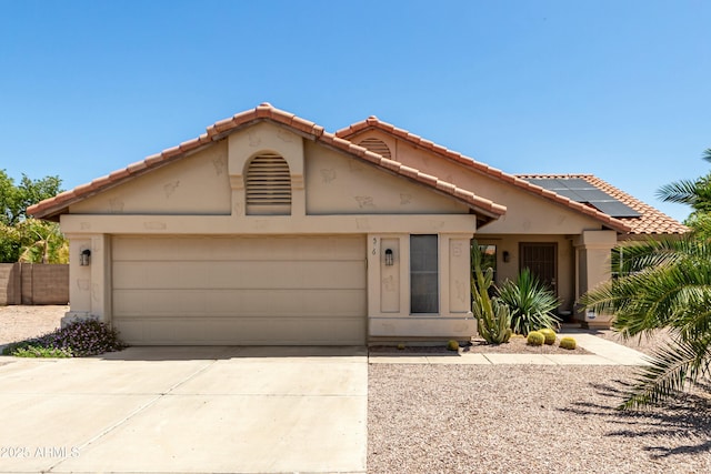 view of front facade featuring a garage, concrete driveway, roof mounted solar panels, and a tile roof