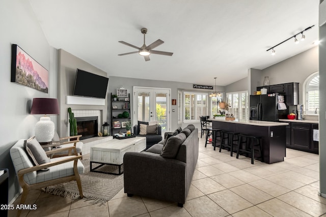 living room with a ceiling fan, vaulted ceiling, track lighting, and light tile patterned floors