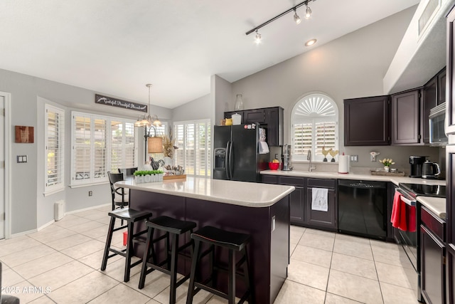 kitchen featuring light countertops, light tile patterned floors, a kitchen island, vaulted ceiling, and black appliances