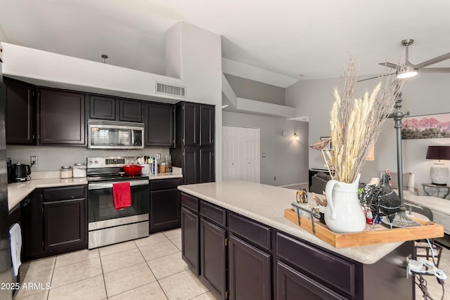 kitchen with appliances with stainless steel finishes, light countertops, light tile patterned floors, lofted ceiling, and visible vents