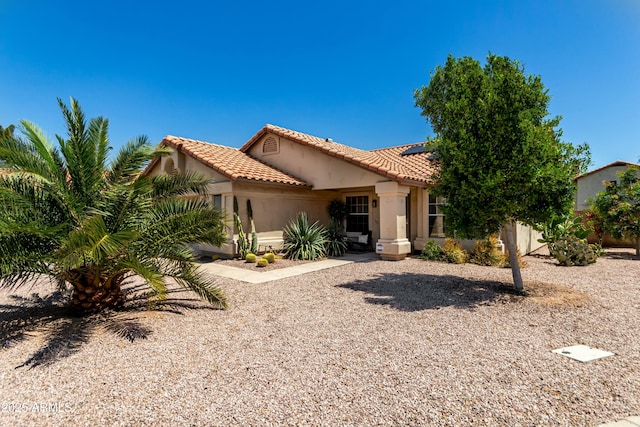 mediterranean / spanish house featuring solar panels, a tile roof, and stucco siding