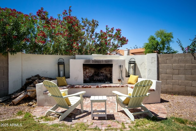 view of patio with an outdoor fireplace and fence