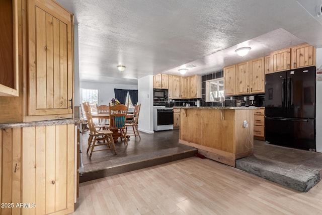 kitchen with light brown cabinets, a center island, a kitchen breakfast bar, wood finished floors, and black appliances