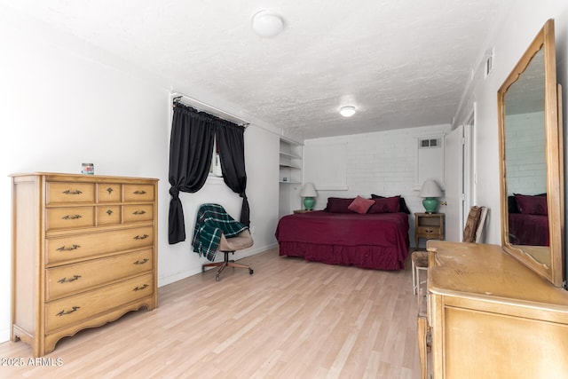 bedroom with visible vents, baseboards, a textured ceiling, and light wood-style flooring