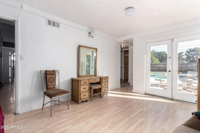 living area featuring light wood-style floors, visible vents, french doors, and baseboards